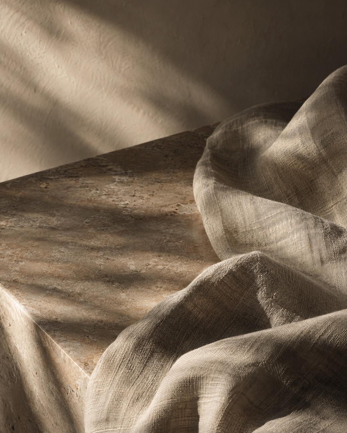 Folded linen in warm window light on a stone surface.